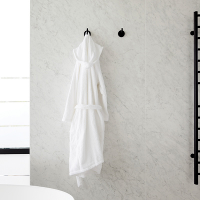 Marble wall tile in bathroom with bathrobe and white bath tub. Design by Knight Varga Interiors | Photography by Janis Nicolay